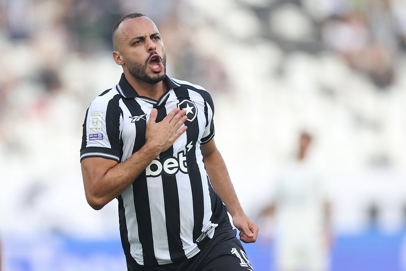 Arthur Cabral celebrates for Botafogo with one hand on the club crest.